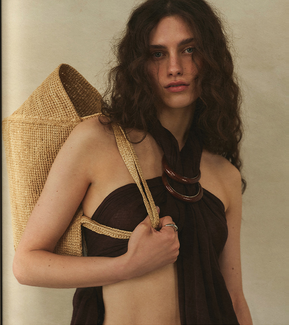 Model with a raffia tote bag on her shoulder, chocolate-brown scarf, hoop necklace and silver ring