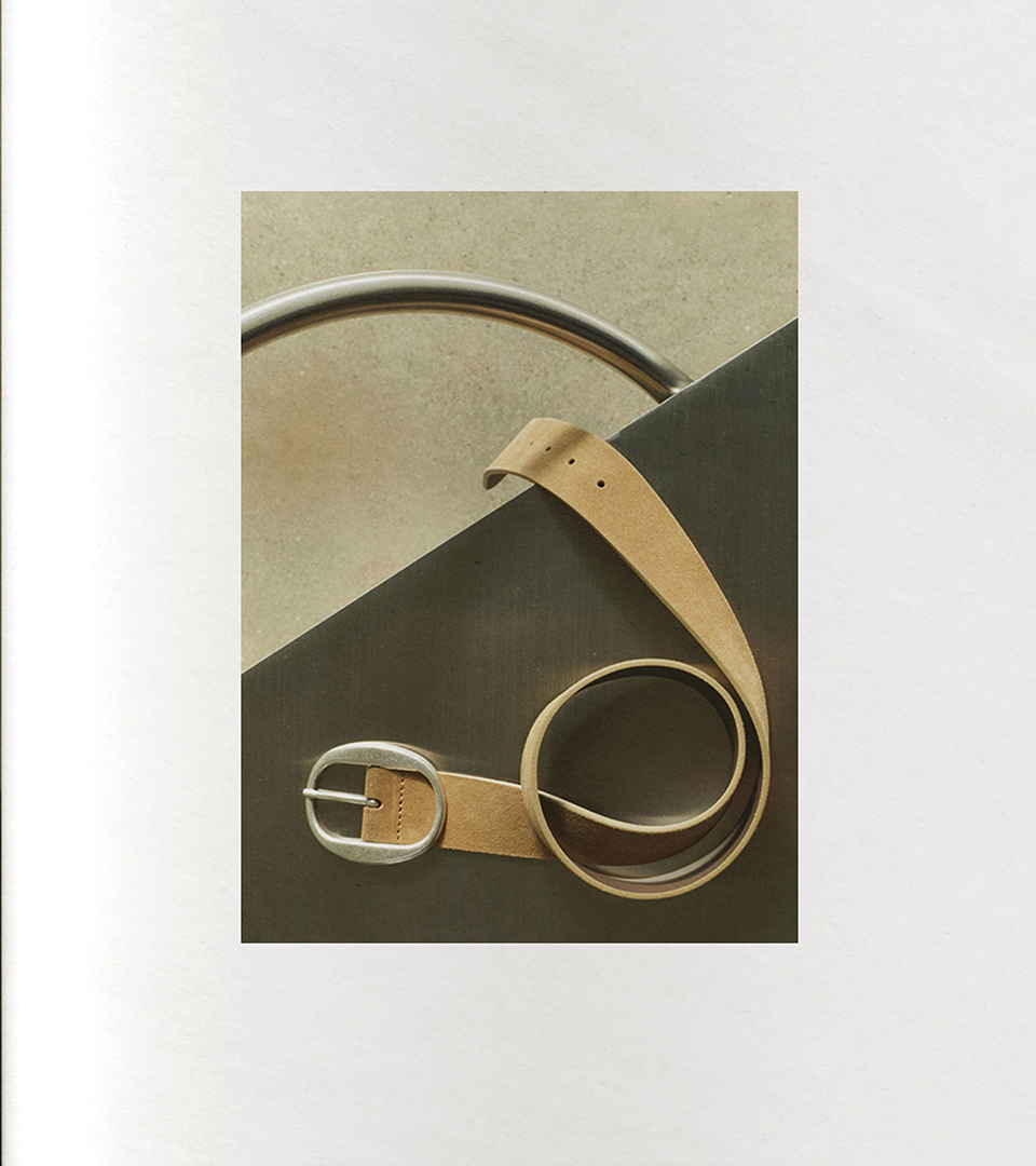 Natural leather belt with silver buckle on a geometric surface
