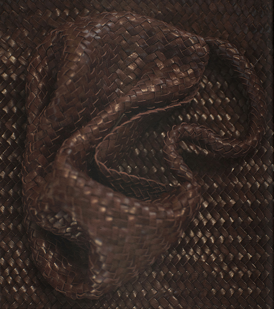 Close-up detail of a dark woven leather crossbody bag