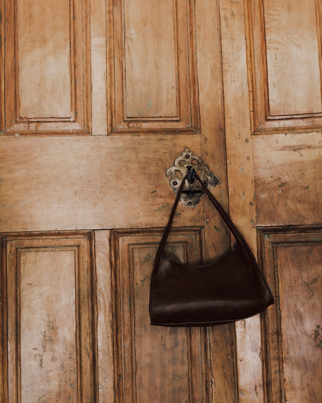 Brown leather bag hanging from a wooden door — Massimo Dutti Fall Treasures