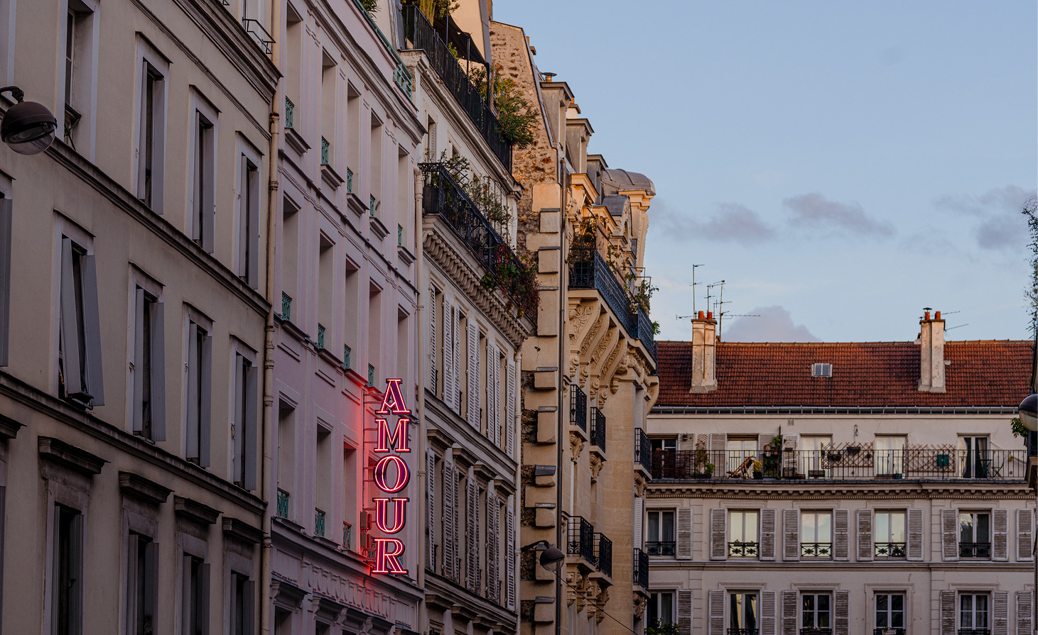 Parisian façade with the neon sign of Hotel Amour at dusk
