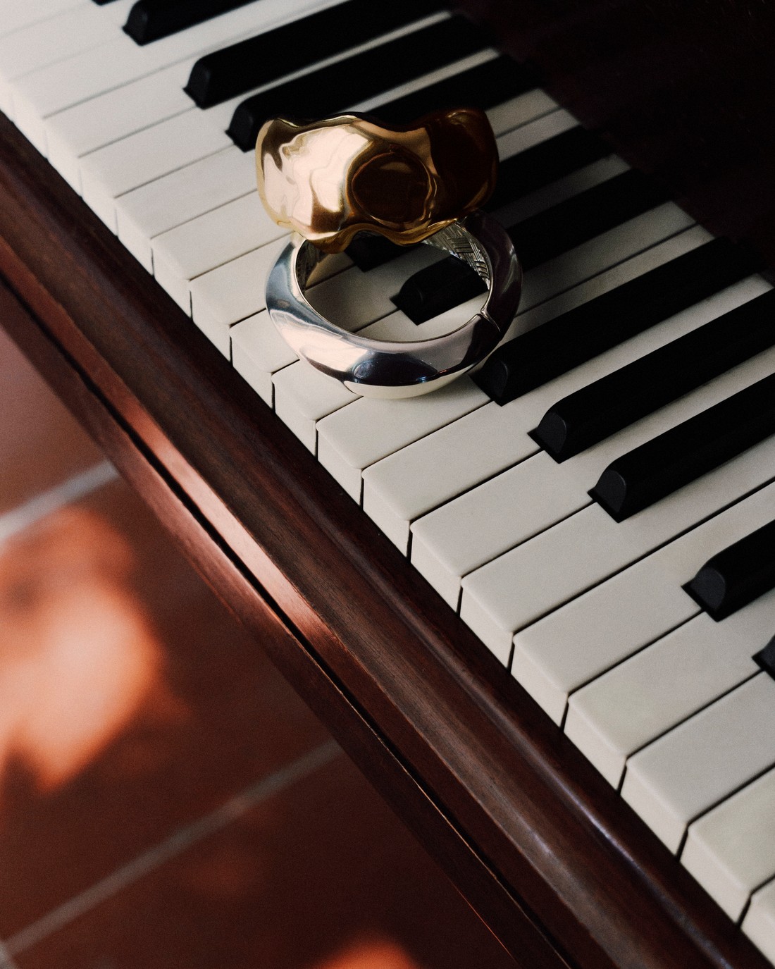 Two metal bracelets on the keys of a piano — Massimo Dutti Fall Treasures