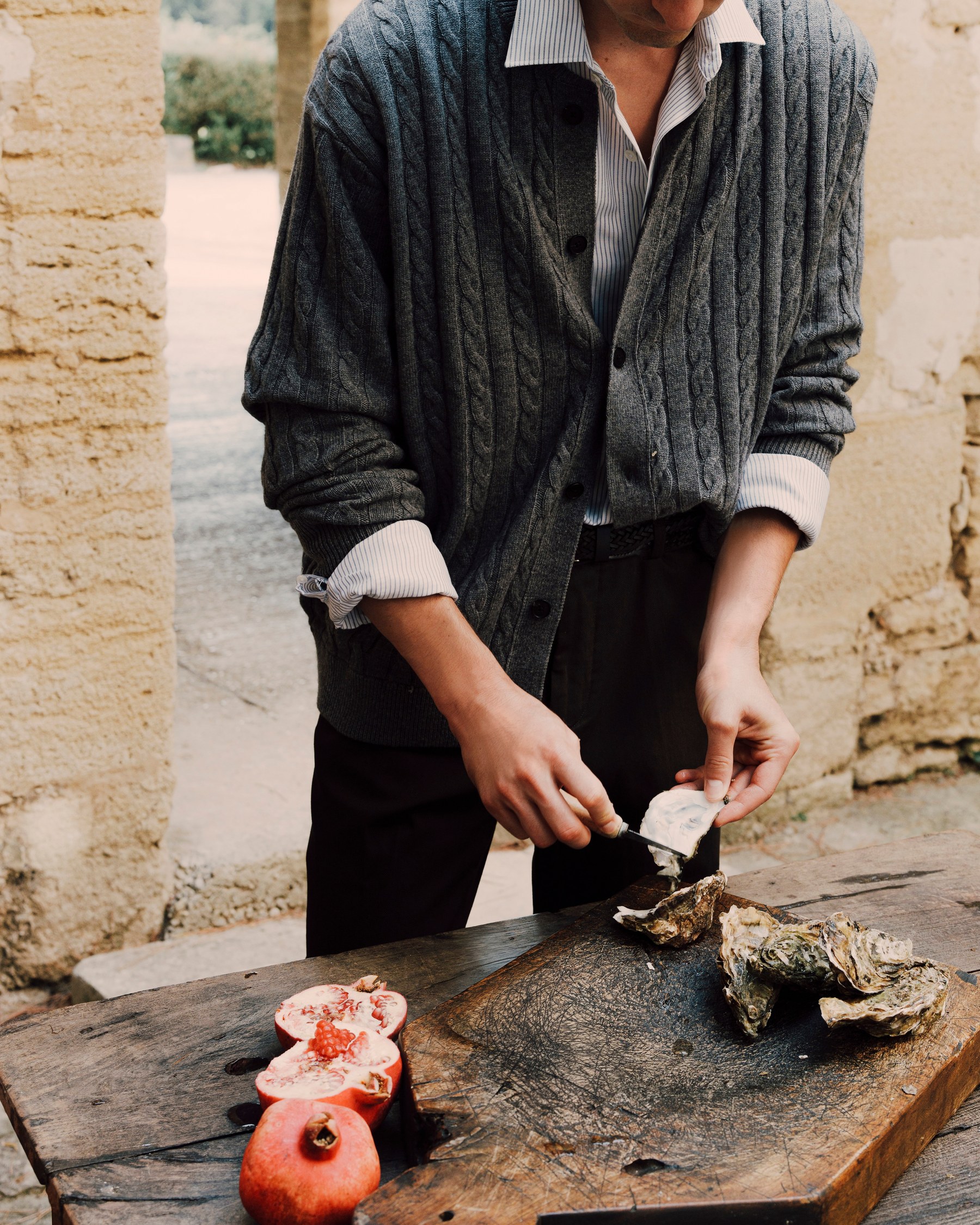 Man in a cable-knit cardigan opening oysters on a wooden table — Massimo Dutti Fall Treasures