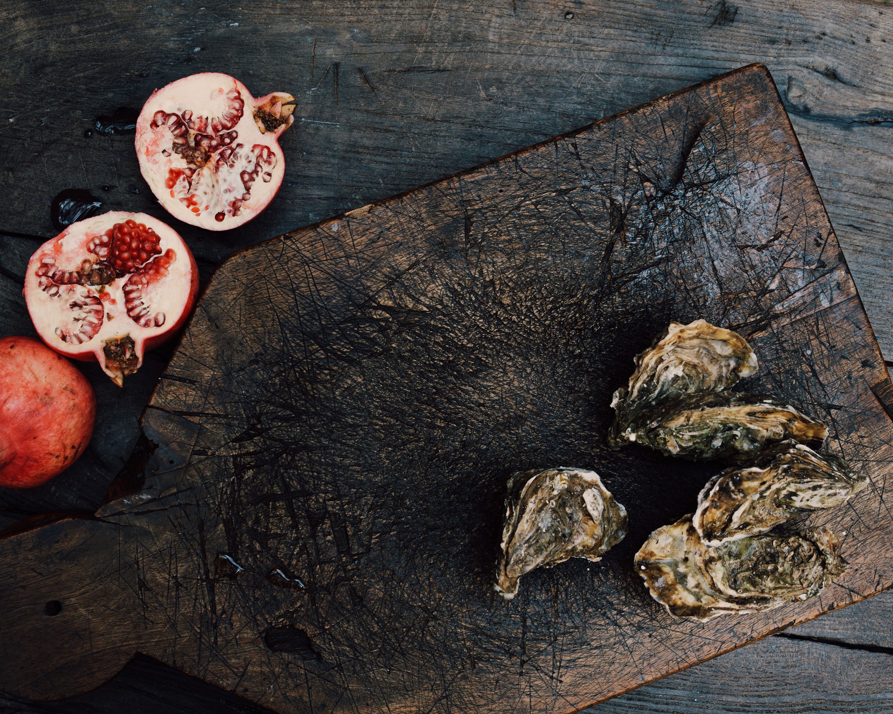 Open pomegranates and oysters on a dark wooden board — Massimo Dutti Fall Treasures