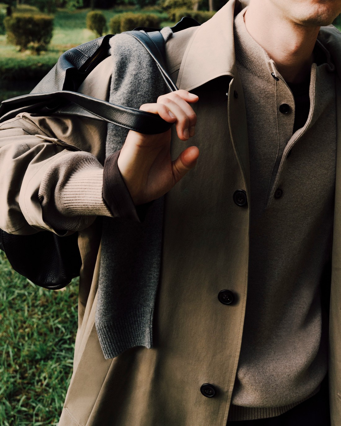 Man in a beige trench coat with a sweater over his shoulder holding a bag strap — Massimo Dutti Fall Treasures