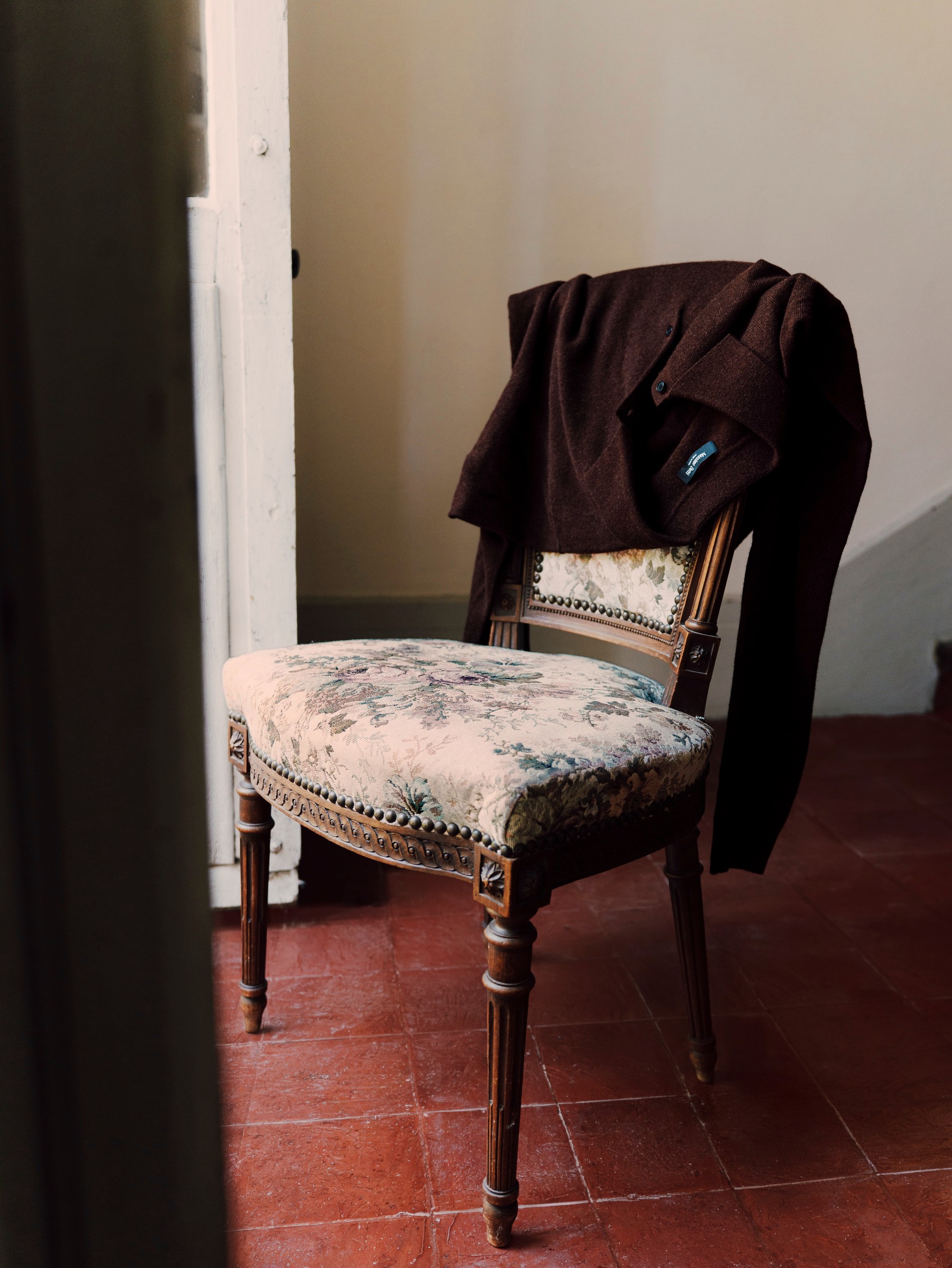 Brown knit jacket on a floral upholstered chair next to a door — Massimo Dutti Fall Treasures