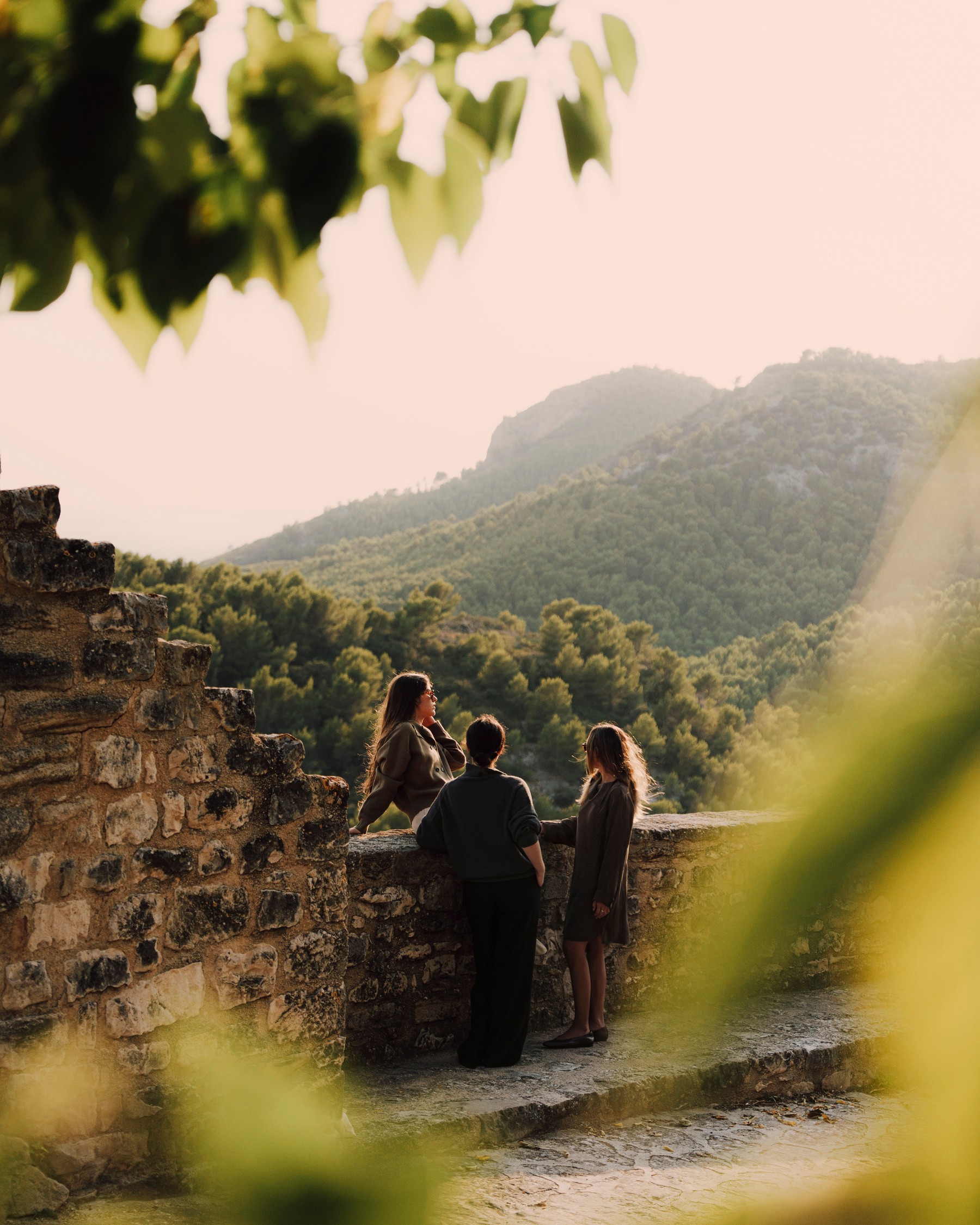 Three women talking at a stone lookout facing the mountains at sunset — Massimo Dutti Fall Treasures