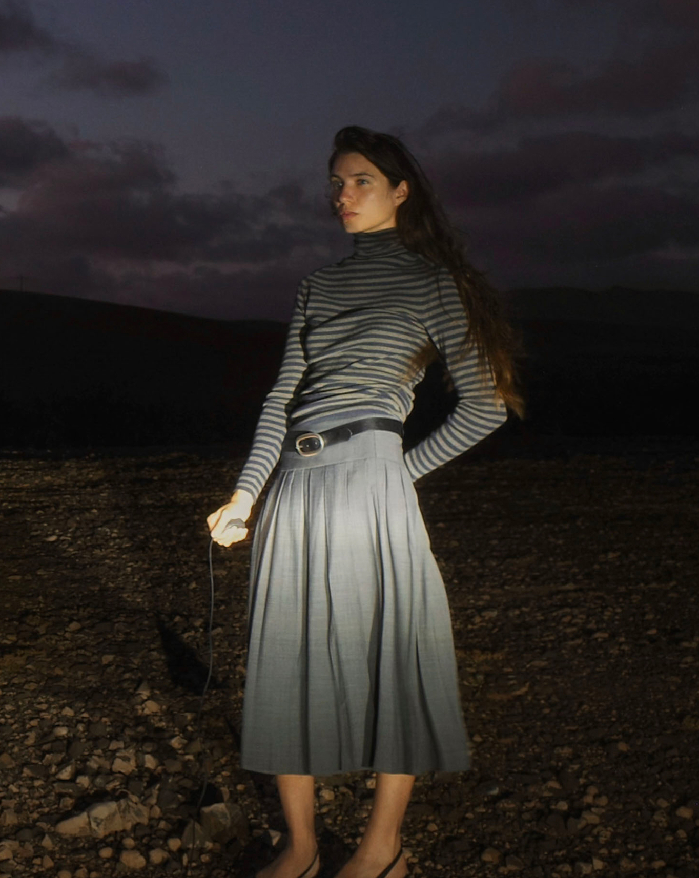 Model in a striped sweater and pleated midi skirt in a volcanic landscape at dusk, Fuerteventura — Massimo Dutti