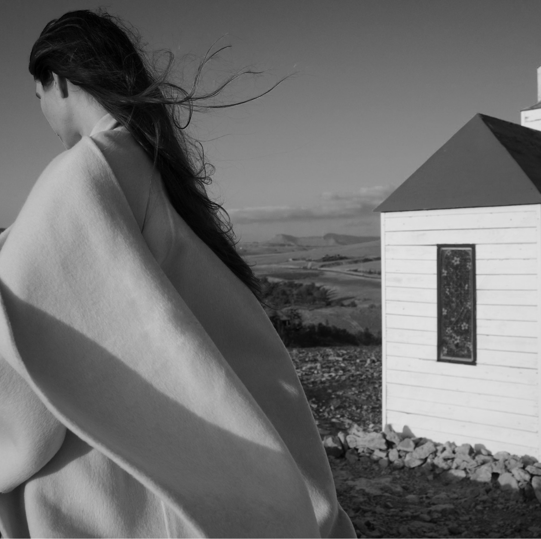 Model from behind in a wool cape beside a white house, Fuerteventura — Massimo Dutti