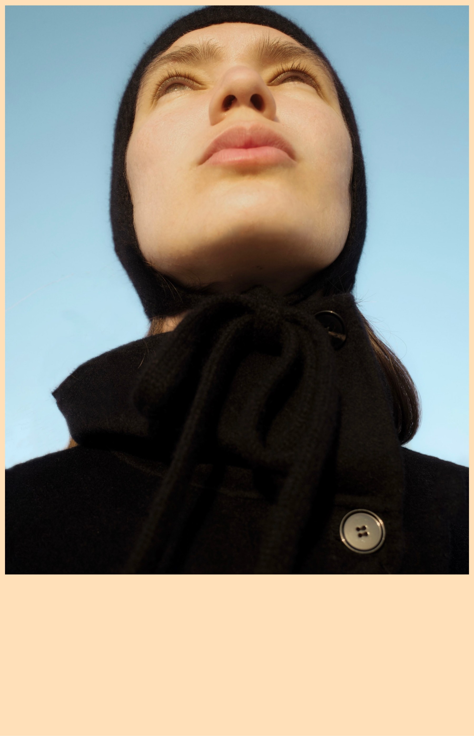 Low-angle portrait in a black knit hat and scarf against a blue sky, Fuerteventura — Massimo Dutti