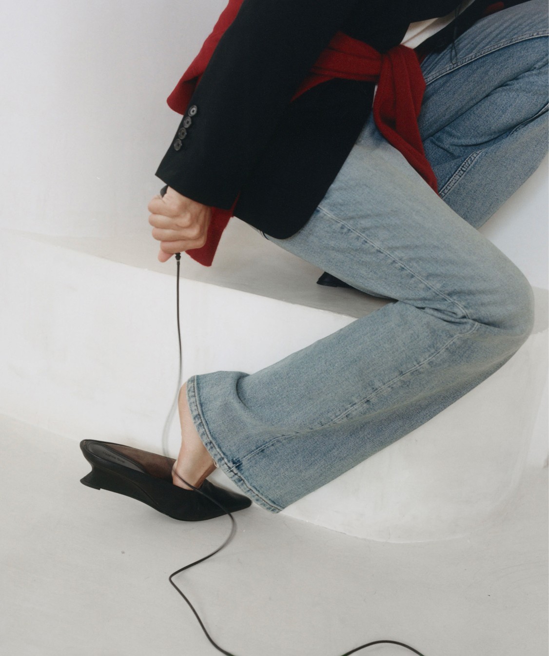 Detail of flare jeans, black blazer and loafers on a stone bench — Massimo Dutti