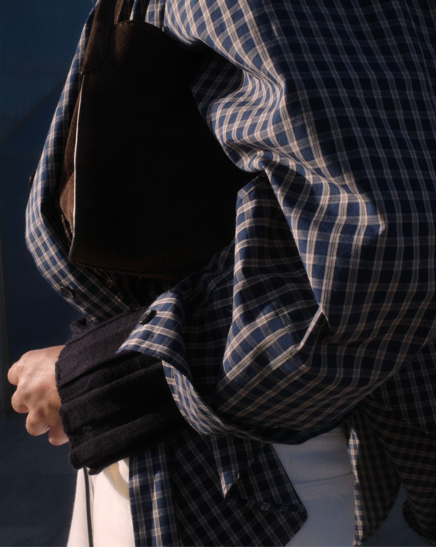 Detail of a navy checked shirt and black leather bag — Massimo Dutti