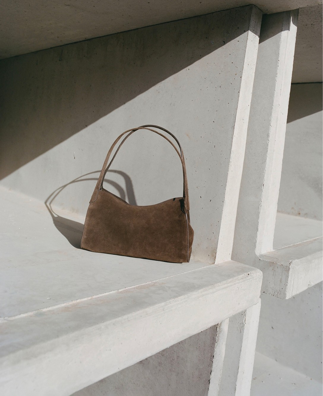 Brown suede bag on a sunlit concrete bench — Massimo Dutti