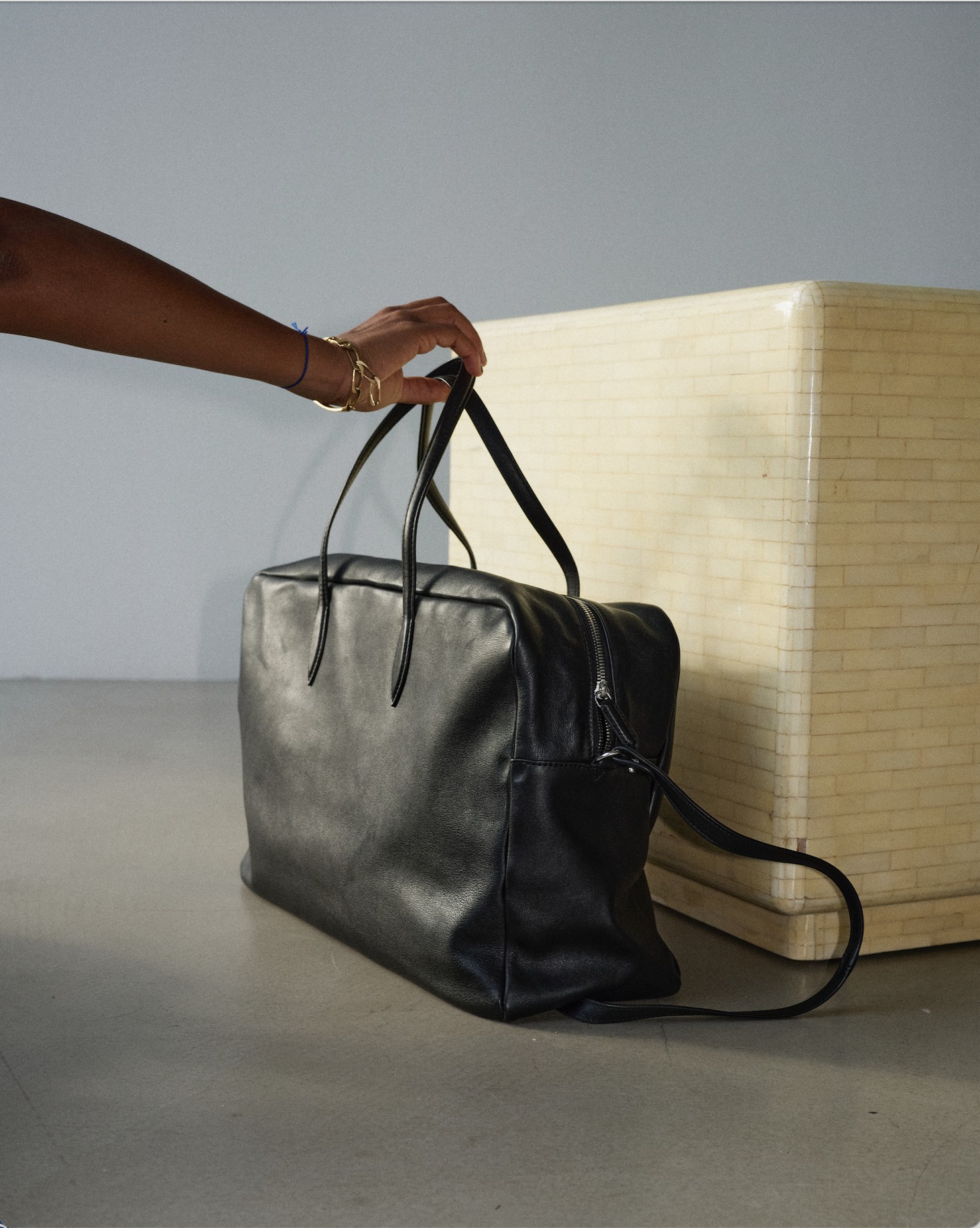 Set design by Giovanna Martial: black leather bag beside a wicker cube — Massimo Dutti