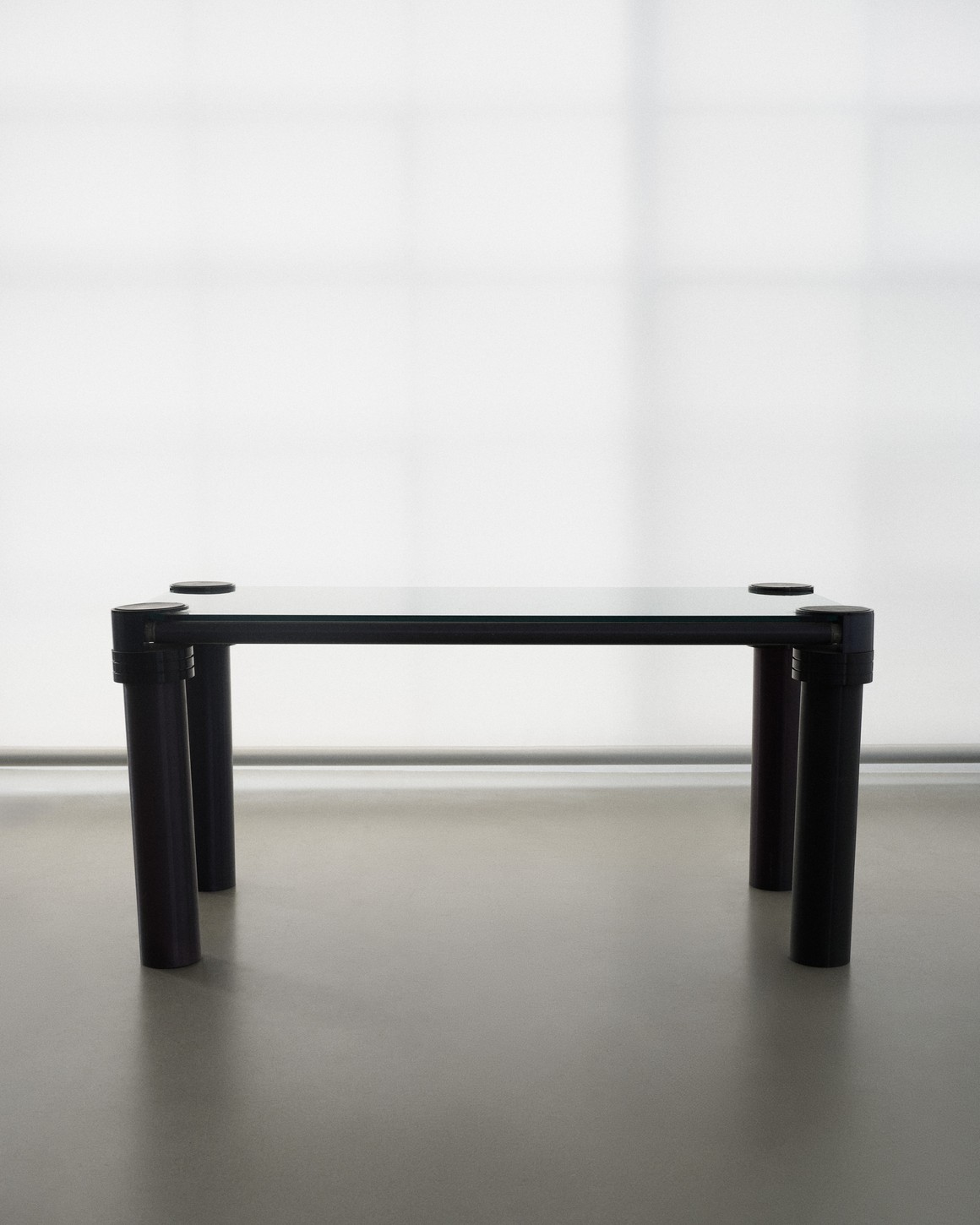 Set design by Giovanna Martial: glass table with black legs in front of a translucent wall — Massimo Dutti