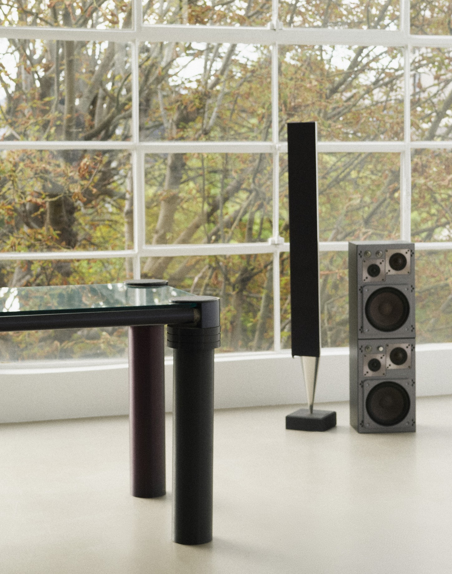 Set design by Giovanna Martial: glass table and speakers in front of a large window — Massimo Dutti