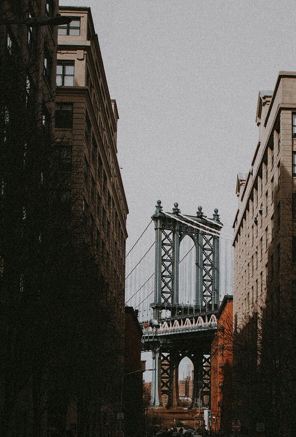 The Manhattan Bridge seen from a street of brick buildings — Massimo Dutti NY Fashion Week