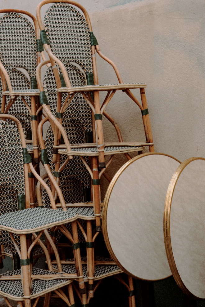 Stacked rattan bistro chairs beside marble tables — Massimo Dutti Paris Fashion Week