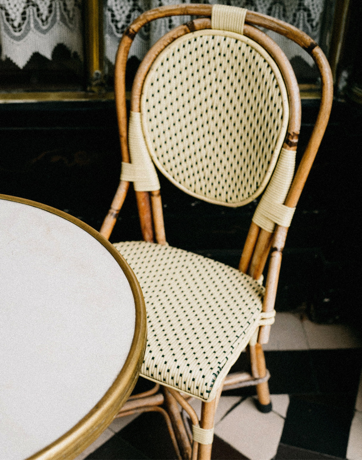 Rattan bistro chair beside a marble table in a Paris café — Massimo Dutti Paris Fashion Week