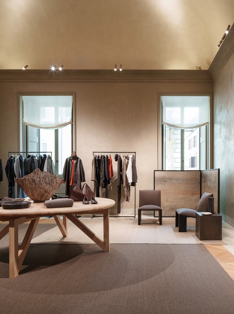 Womenswear room with a central table, clothing rails and armchairs beneath a vault — Massimo Dutti Rome