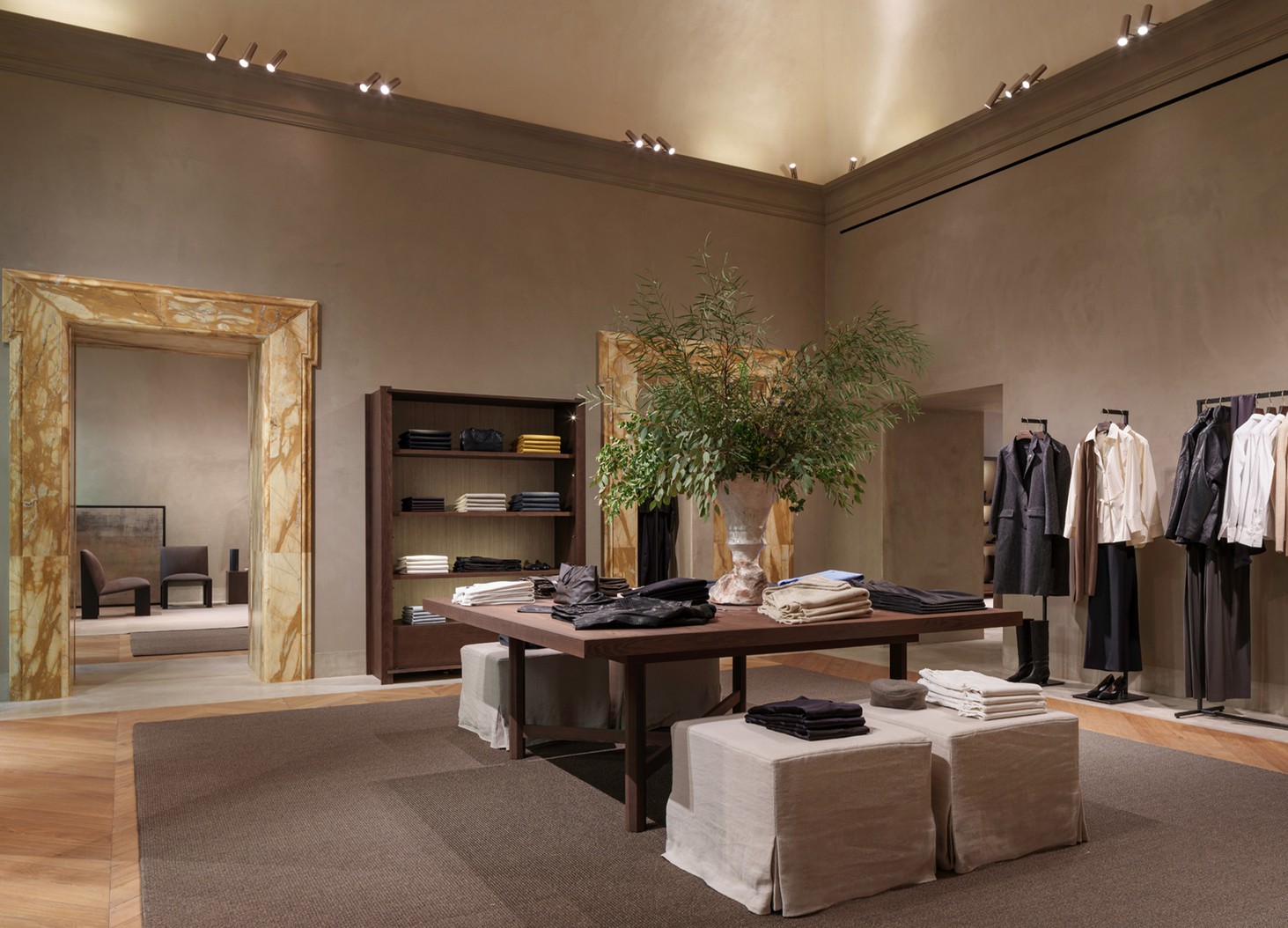 Womenswear room with a marble doorframe, central table and mannequins — Massimo Dutti Rome