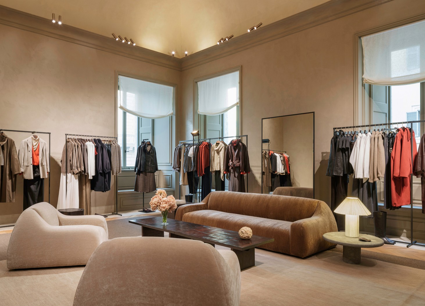 Womenswear room with curved sofas, clothing rails and windows with blinds — Massimo Dutti Rome