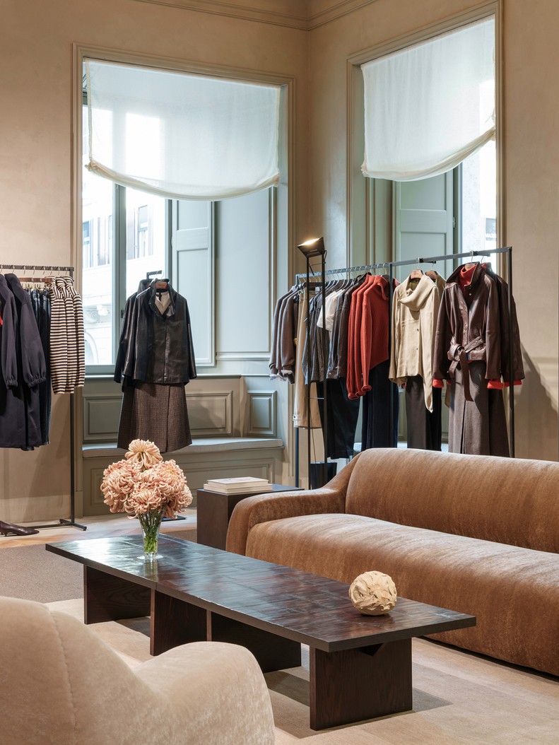 Seating area with a sofa, coffee table and womenswear rails — Massimo Dutti Rome