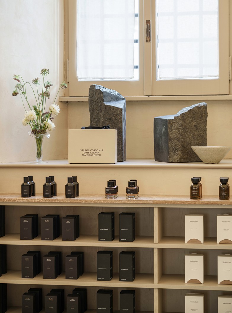Perfume bottles and boxes beneath a window with flowers and stones — Massimo Dutti Rome
