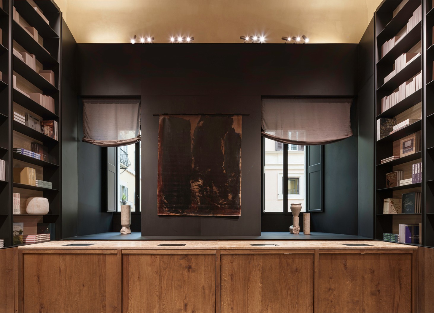 Bookshop with a wooden counter, black shelving and windows — Massimo Dutti Rome