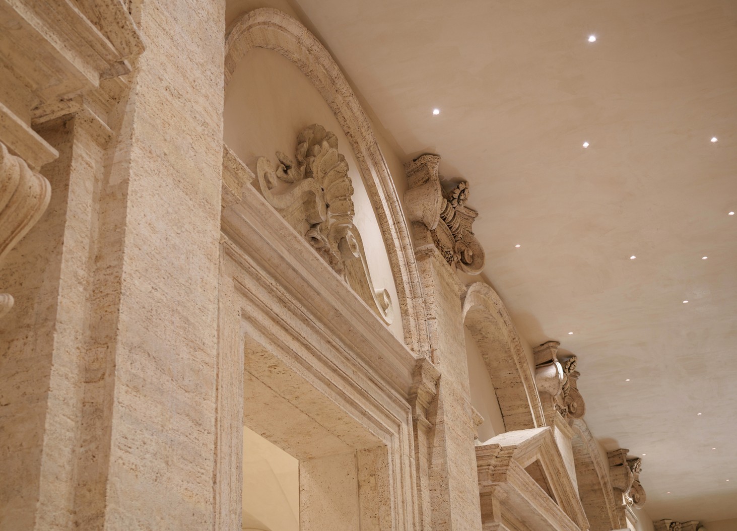 Detail of travertine capitals and a ceiling with spotlights — Massimo Dutti Rome