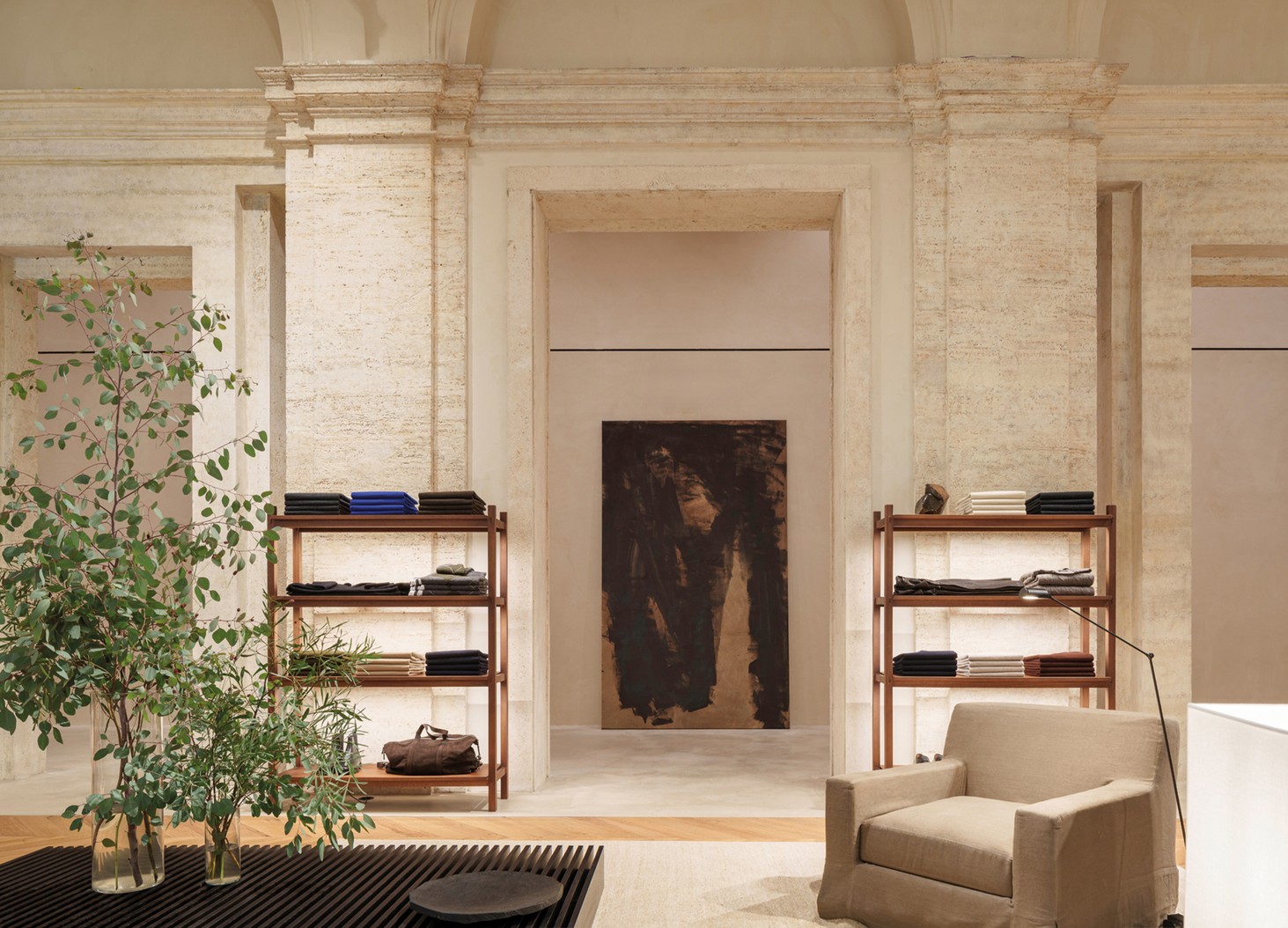 Menswear room with shelving, an armchair and a canvas between pilasters — Massimo Dutti Rome