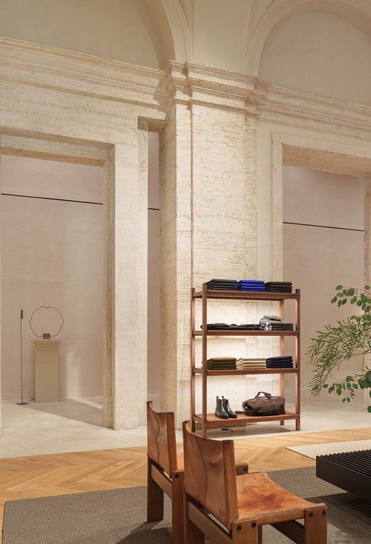 Wooden shelving with accessories, a leather chair and branches beside the pilasters — Massimo Dutti Rome