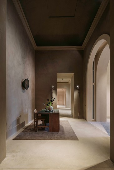 Enfilade of arched rooms with a rug and a wooden table — Massimo Dutti Rome