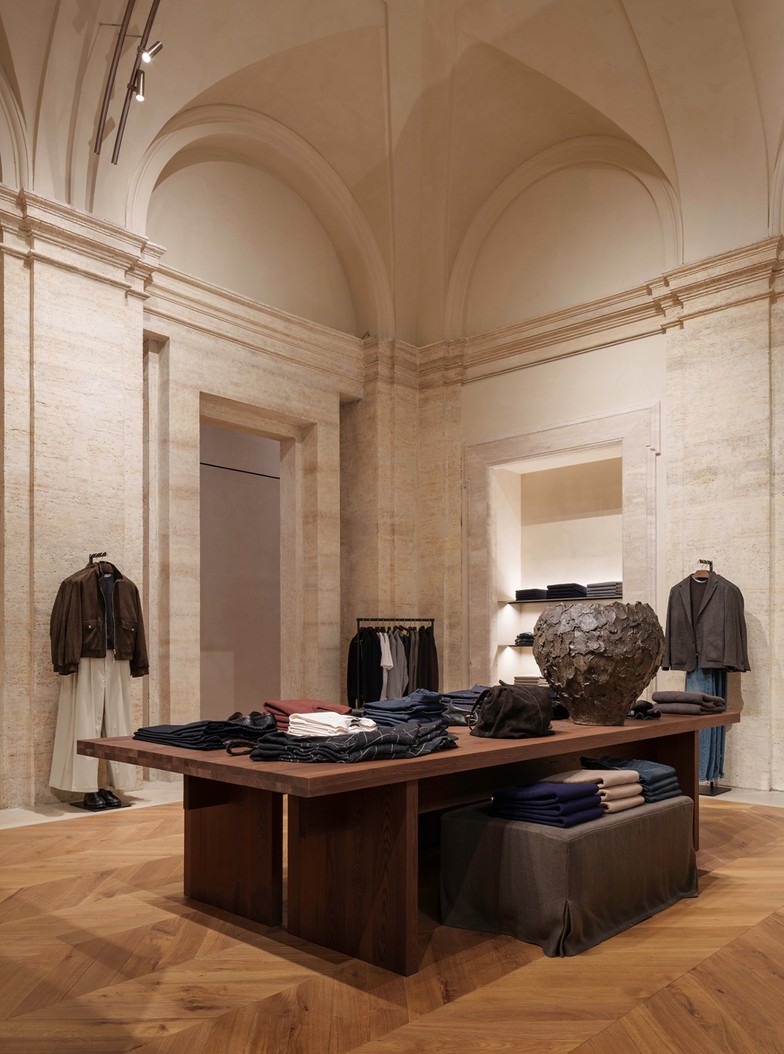 Central menswear table with folded garments and clothing rails behind — Massimo Dutti Rome