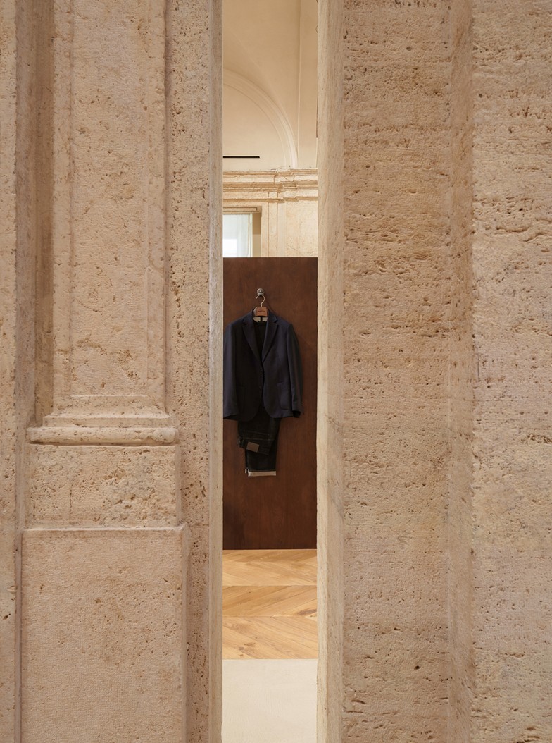 Jacket hanging between two travertine pilasters — Massimo Dutti Rome