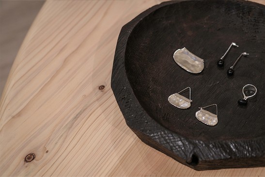 Black wooden tray with earrings and rings on a light wooden table — Massimo Dutti Rome